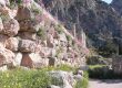 Ancient archaeological site of Delphi, featuring the ruins of the Temple of Apollo, surrounded by mountains and lush valleys in Greece.